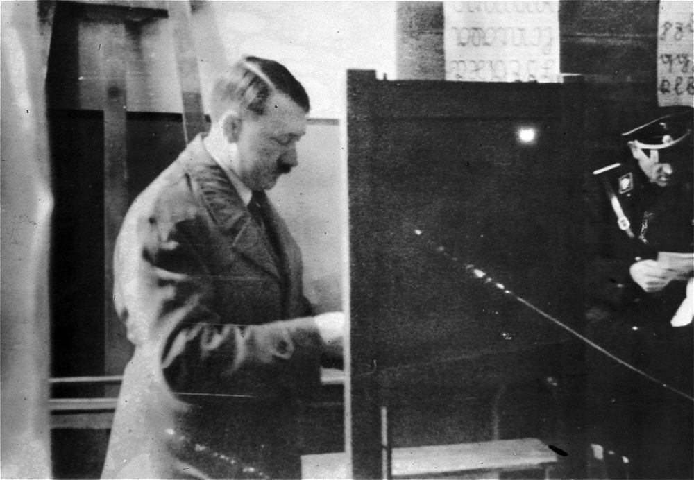 Adolf Hitler casts his vote at a polling station set up in a schoolroom for the Reichstag elections